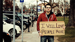 teenager holding inspirational sign on sidewalk