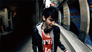 Joshua Micah singing in Barcelona alley wearing red t-shirt and jacket
