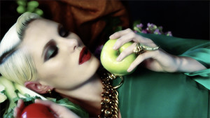 blond fashion model in studio laying on table eating apple