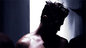 male fashion model in studio topless tilting head closeup