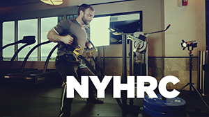 athlete pulling sled at sports club with NYHRC graphic