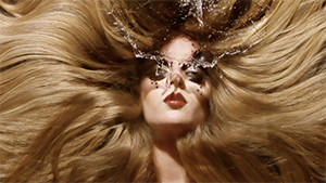 Fashion model in studio with huge hair and water in front of face