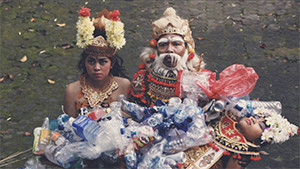 Balinese girl and father in traditional costumes and makeup carrying dead girl enveloped in plastic