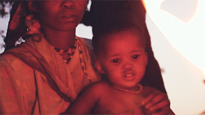 bushmen mother with child by fire