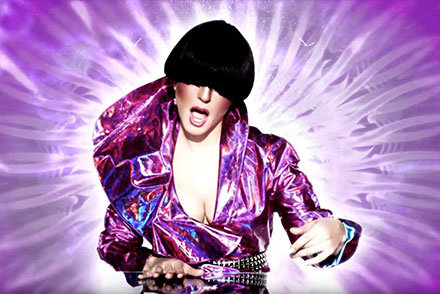 Silvia Tosun performing in music video with wig covering eyes and graphic background