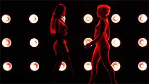 two models walking towards each in red lighting